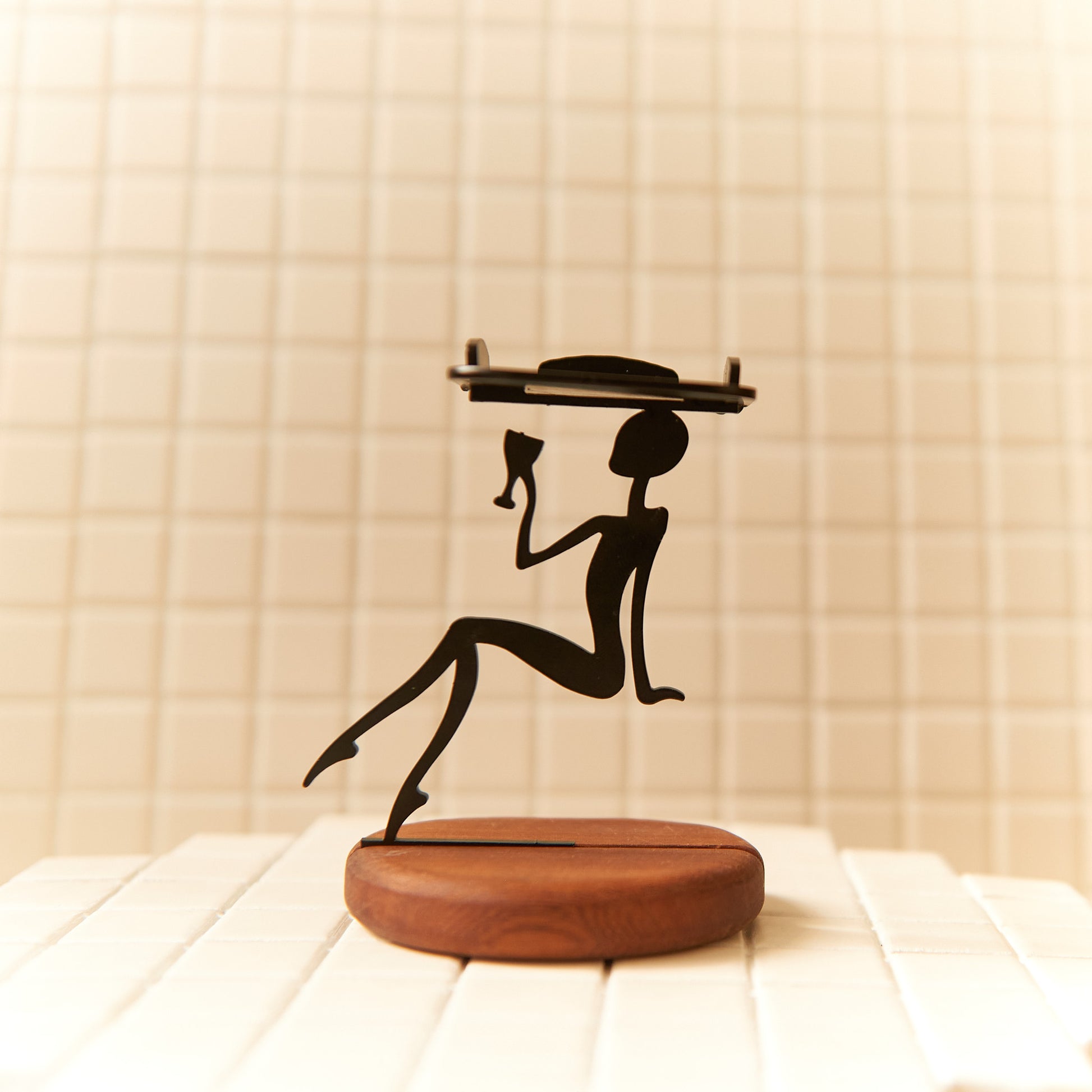 Handmade extraterrestrial candle holder with wooden base and sleek black silhouette design.