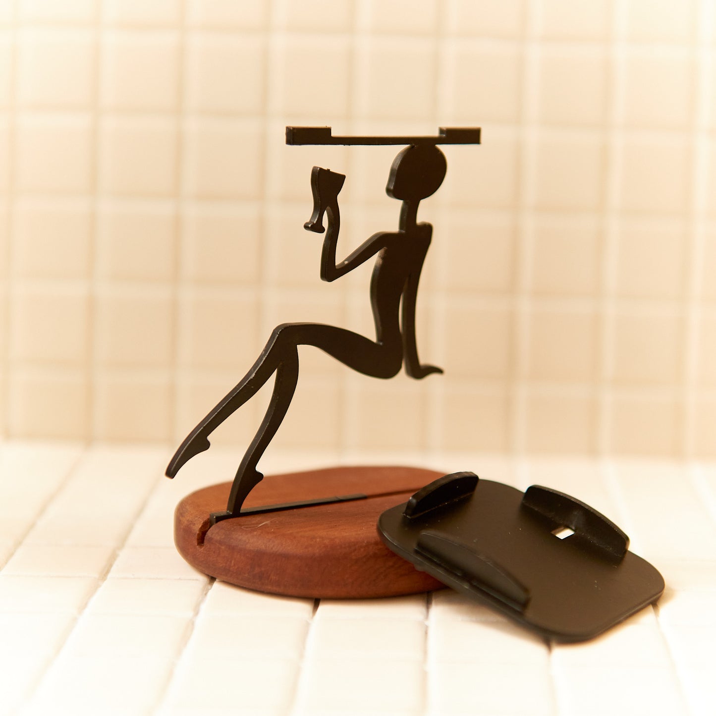 Minimalist alien figurine holding a wine glass, crafted in matte black metal on a round wooden base — handmade by Zeugman.