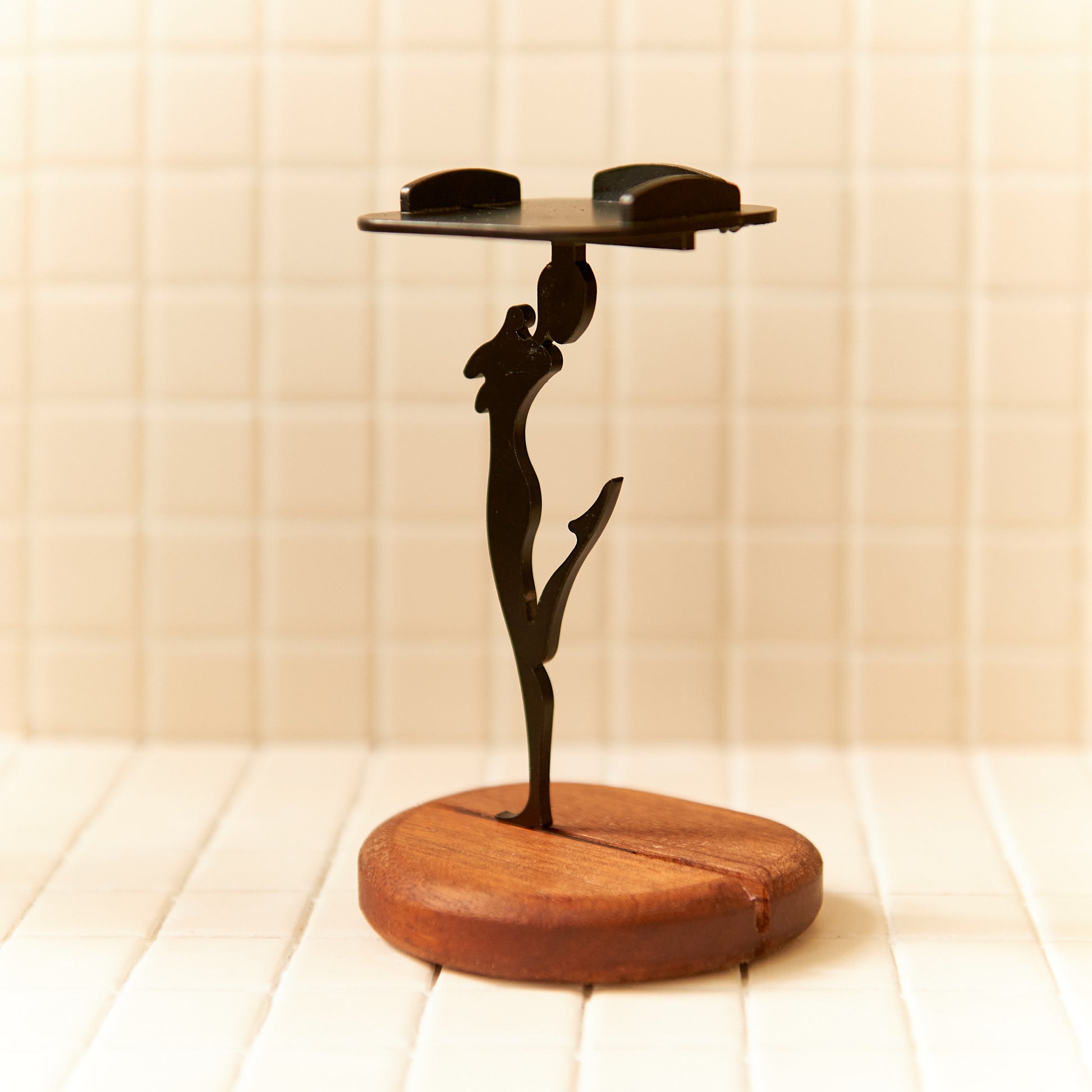 Unique extraterrestrial art candle stand featuring a dancing alien silhouette crafted from metal, balanced elegantly on a round mahogany base.