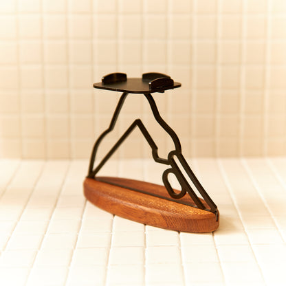 Metal yoga figure candle holder on mahogany base, symbol of grounding and flow.