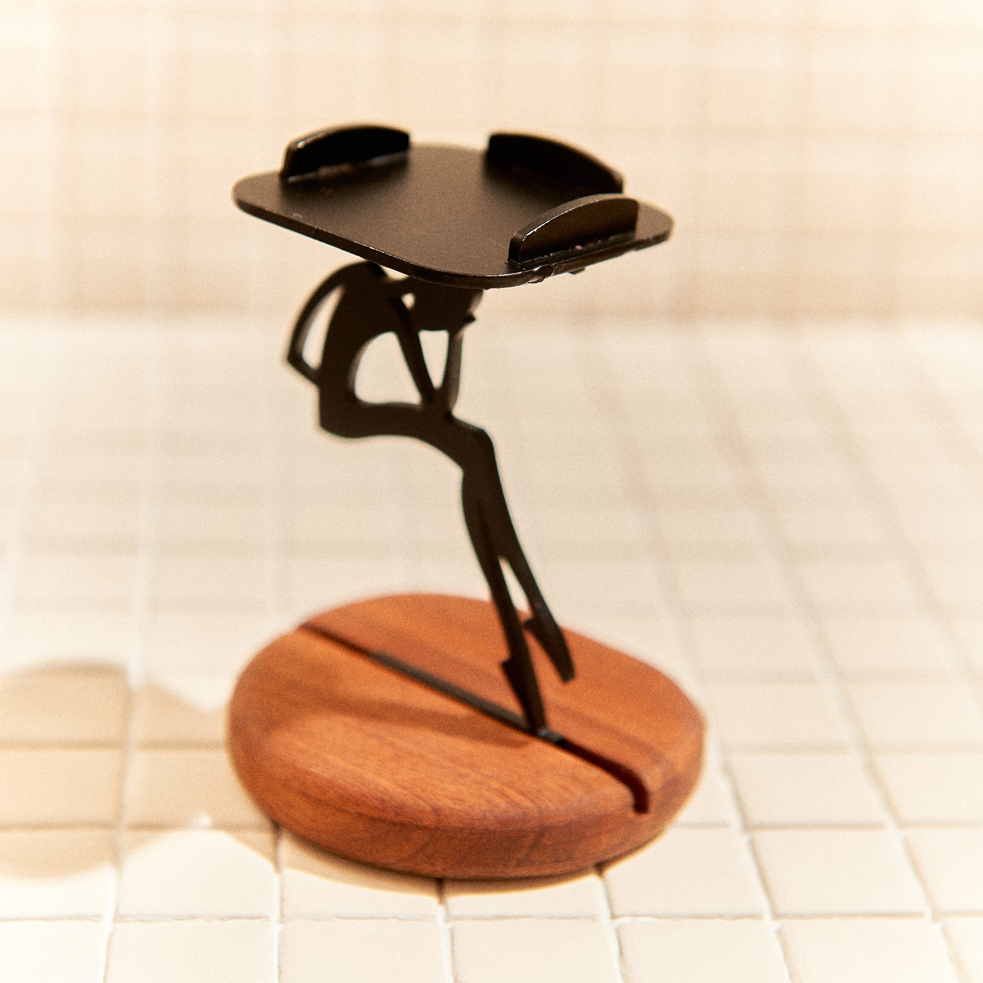 Metal alien figure candle holder on mahogany base, artistic home accent.