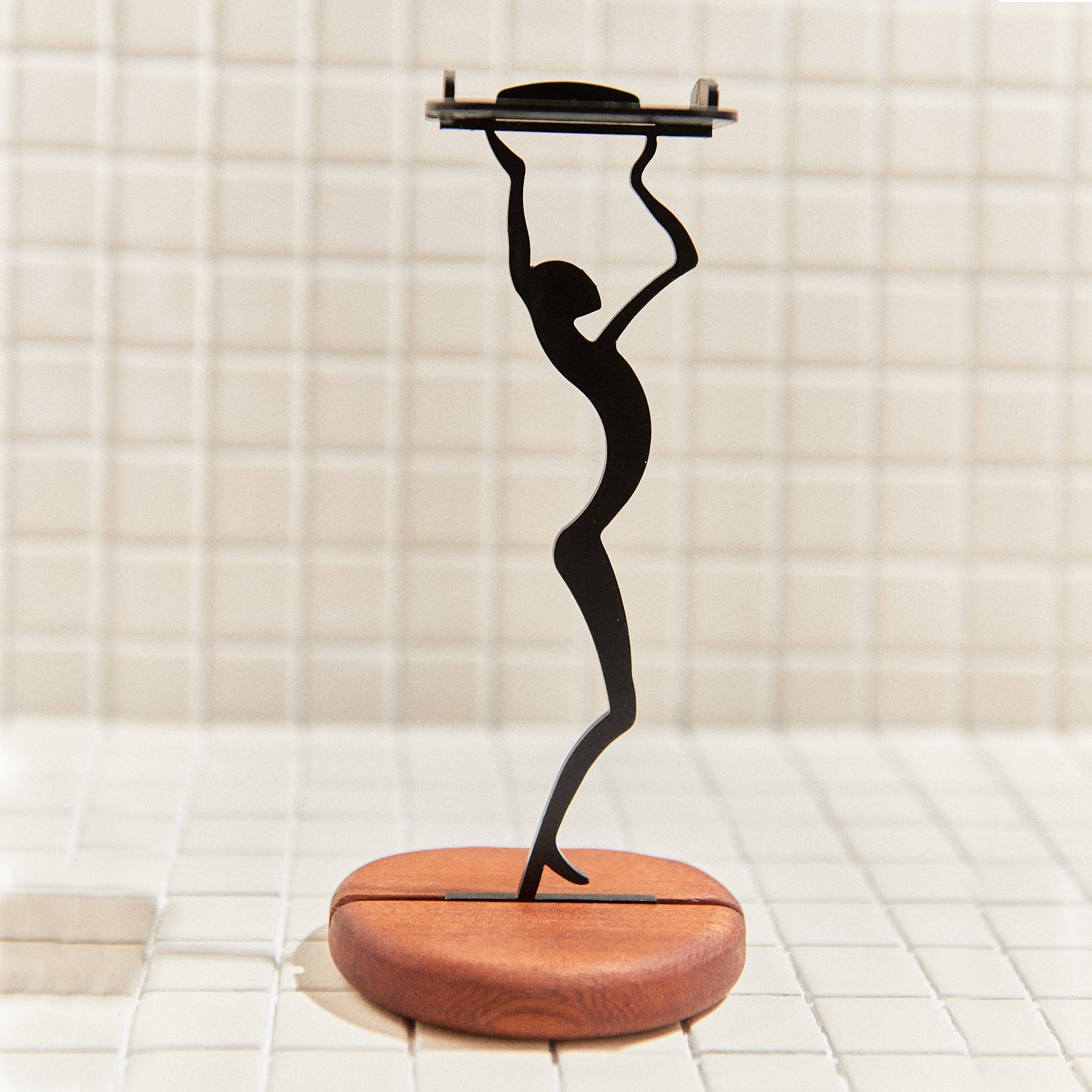 Close-up of alien-shaped metal candle holder holding a tealight, on polished mahogany base – modern sci-fi home decor.